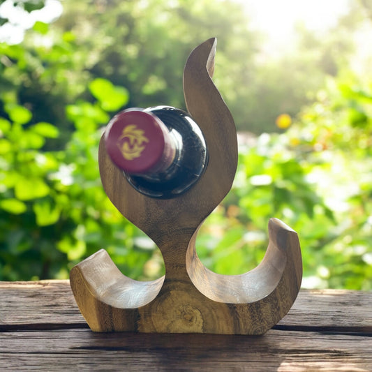 Wooden wine bottle holder with a bottle of red wine against a blurred green outdoor background