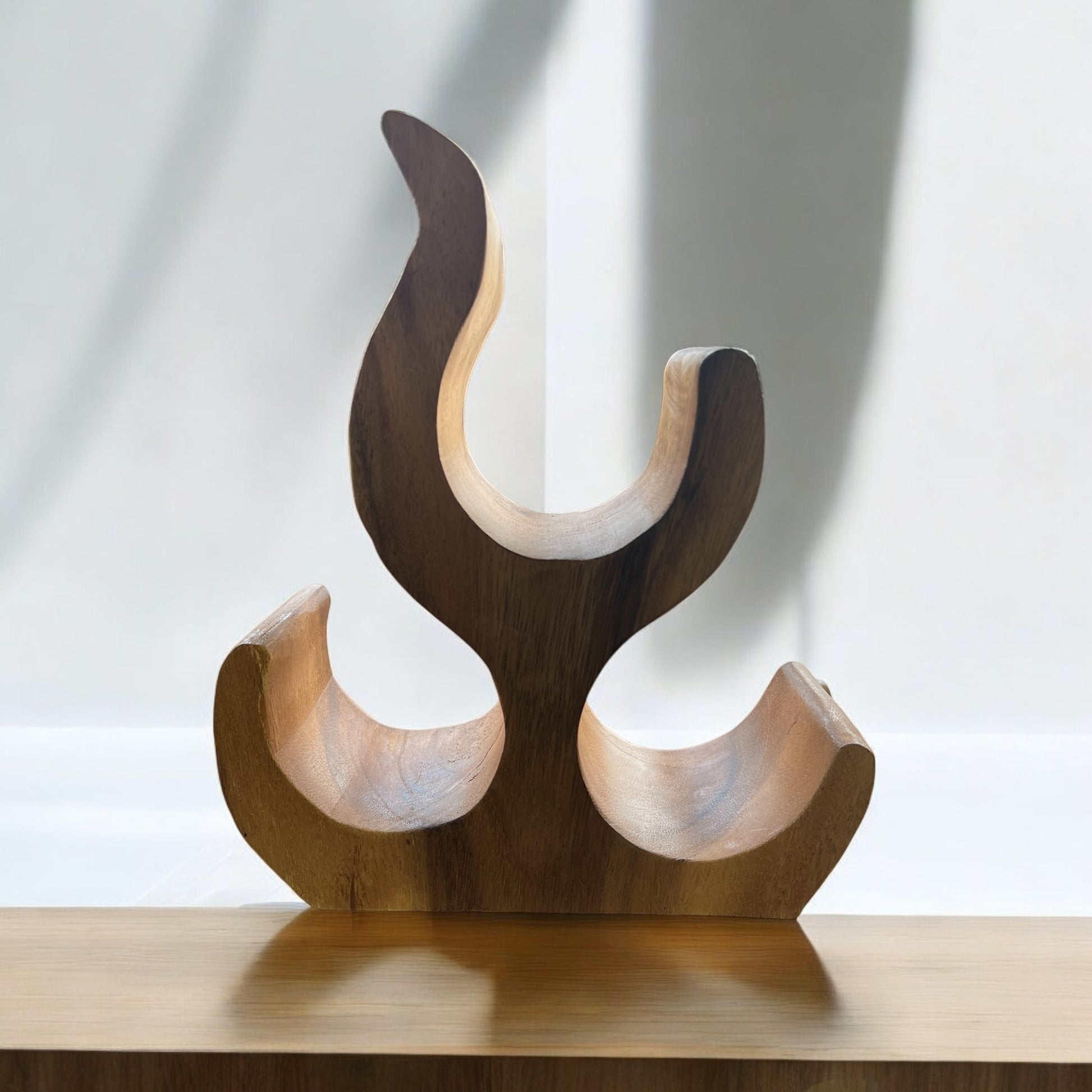 Wooden sculpture with abstract design on a reflective surface