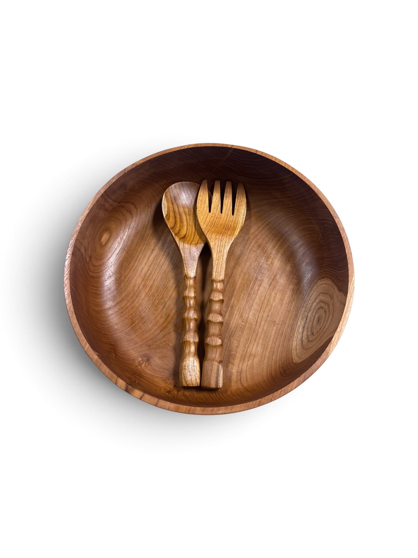 A top-down view of a round teakwood salad bowl containing a matching wooden spoon and fork, set against a plain white background.