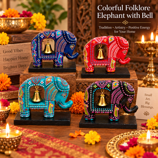 Four hand-painted wooden elephant figurines with hanging gold bells, decorated with intricate folk art patterns in blue, red, teal, and purple, arranged on a wooden table with lit candles and marigolds.