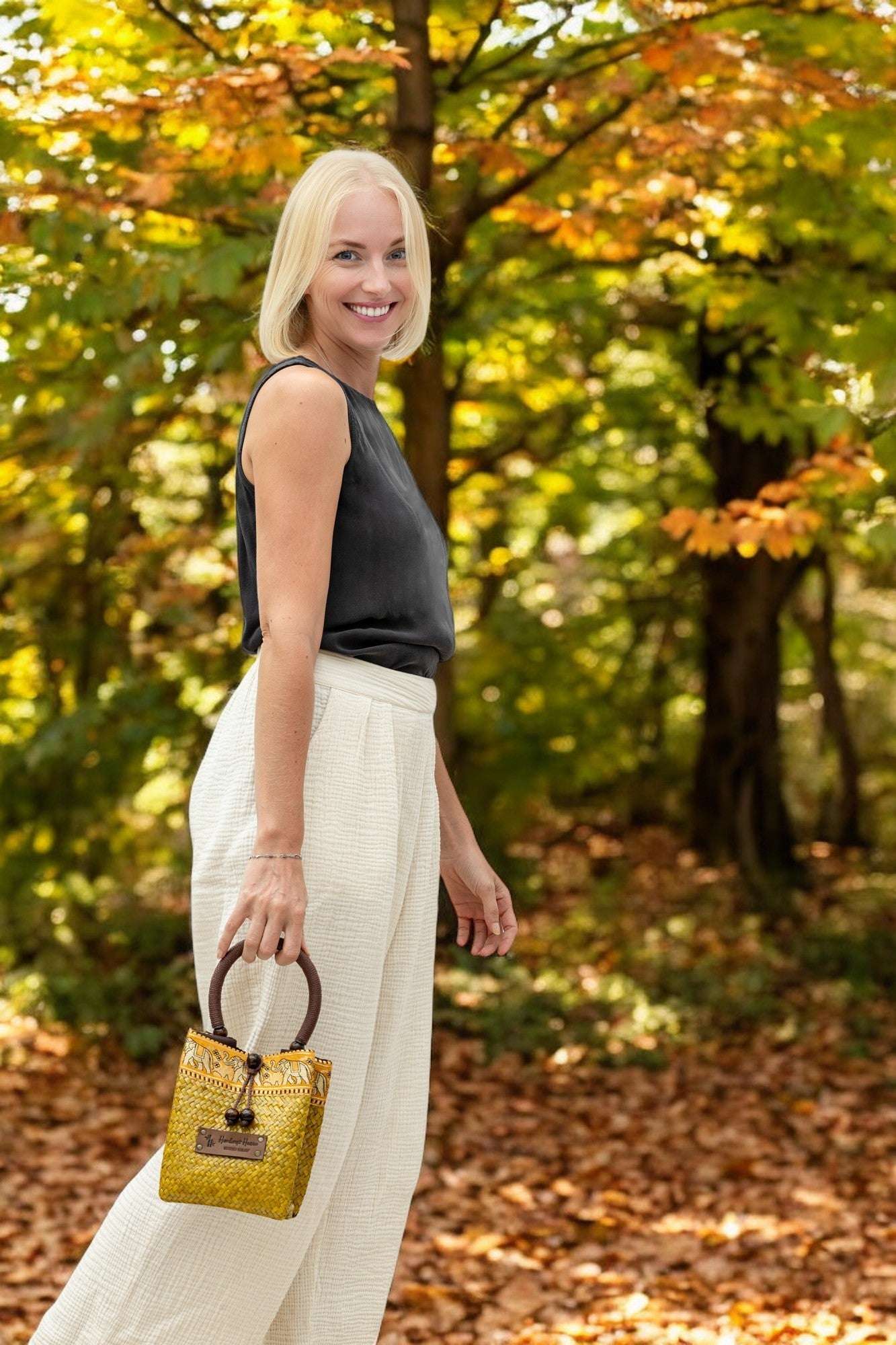 Woman holding a yellow mini top handle handbag in an autumn forest