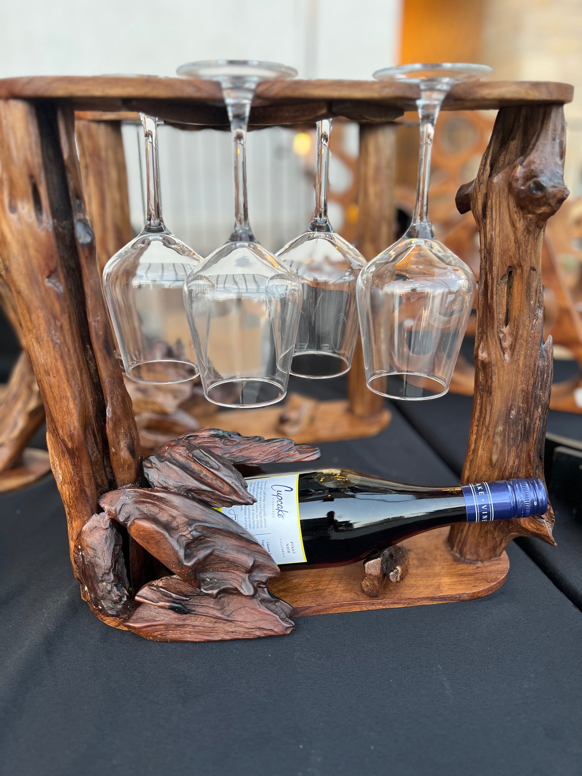 Wooden wine rack with four glasses and a bottle on a dark surface