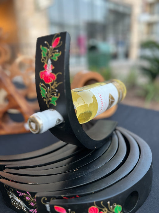 Decorative wine bottle holder with floral designs on a blurred background