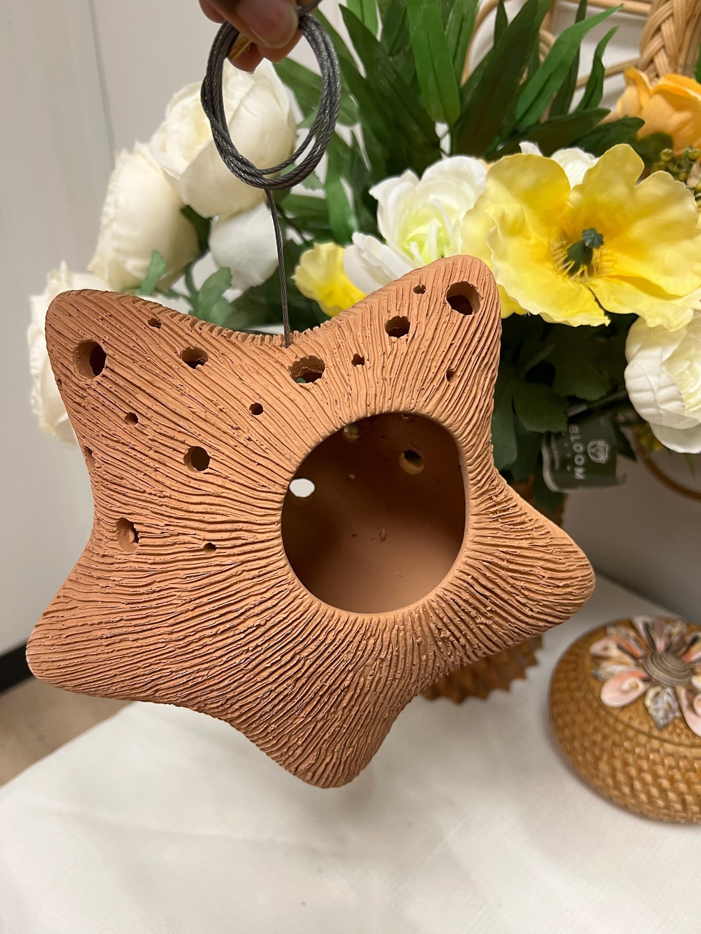 Star-shaped terracotta pot with floral arrangement in the background