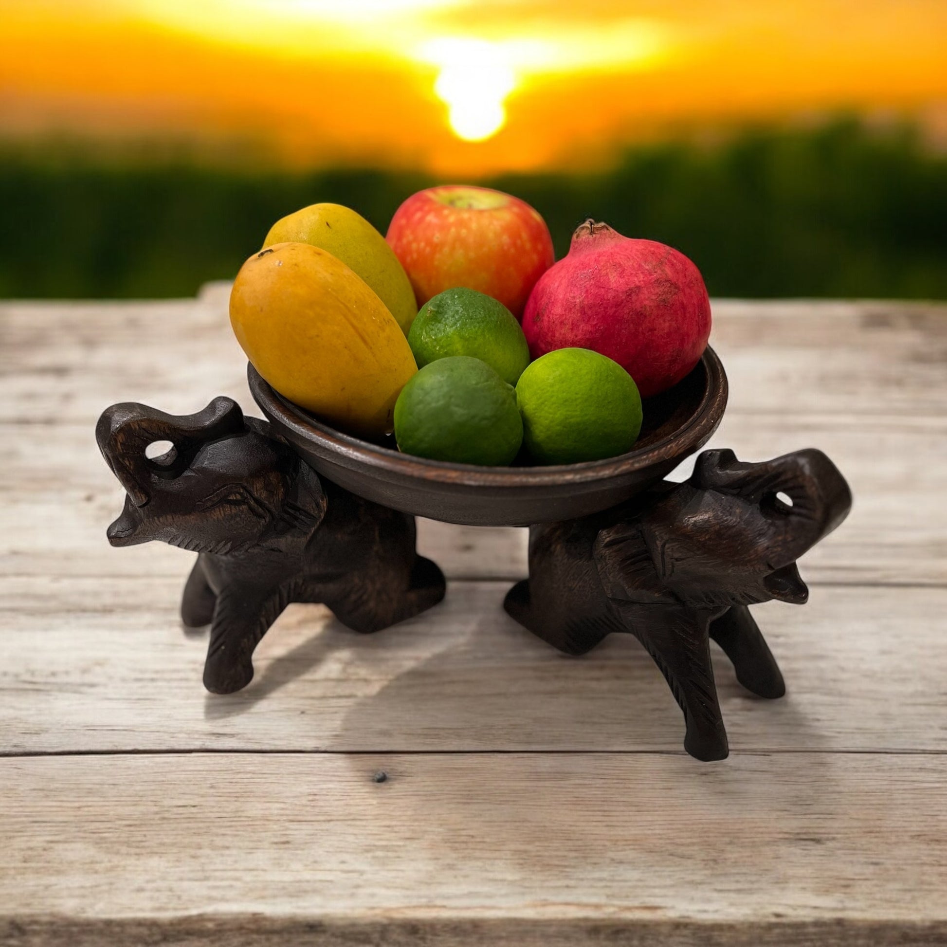 Bowl of fruits on a Triple Elephant Round Wood Tray Stand with sunset background