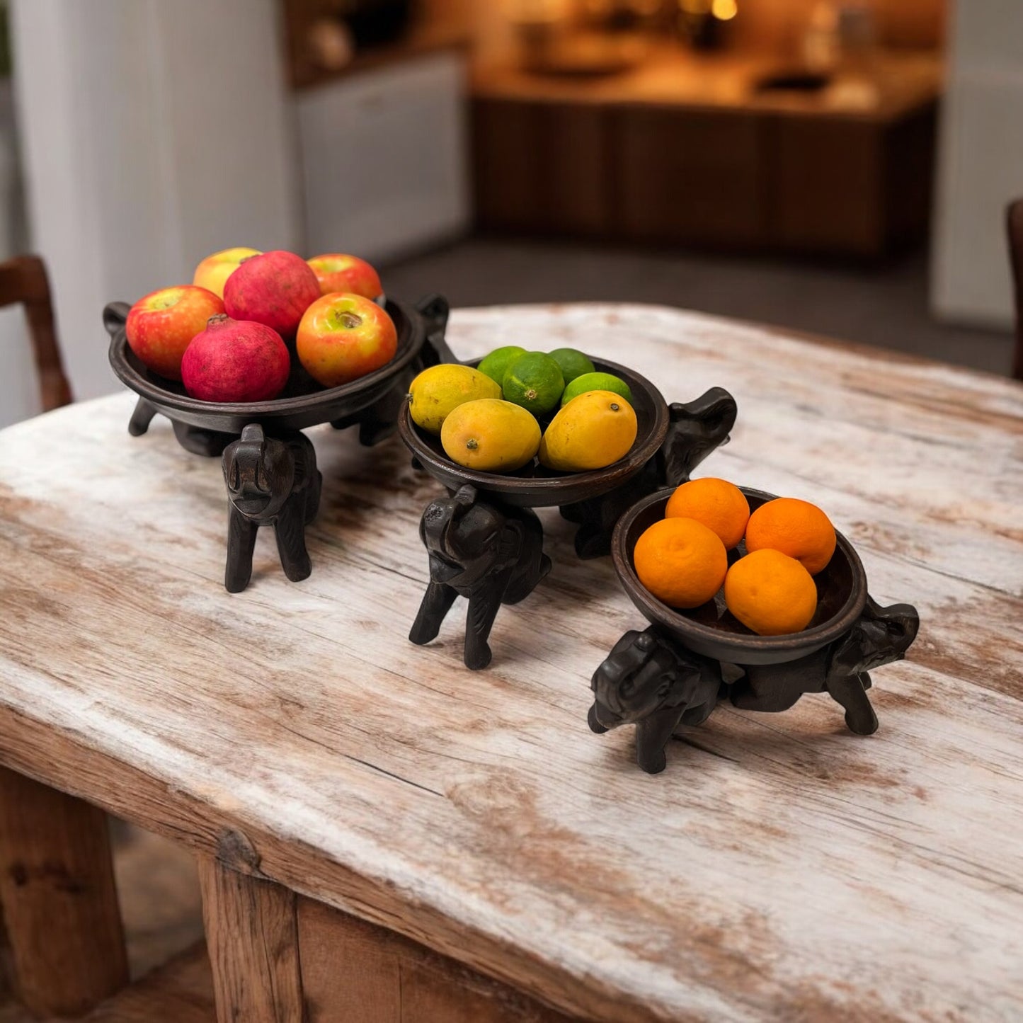 Triple Elephant Round Wood Tray Stand with apples, oranges, and lemons on a wooden table.