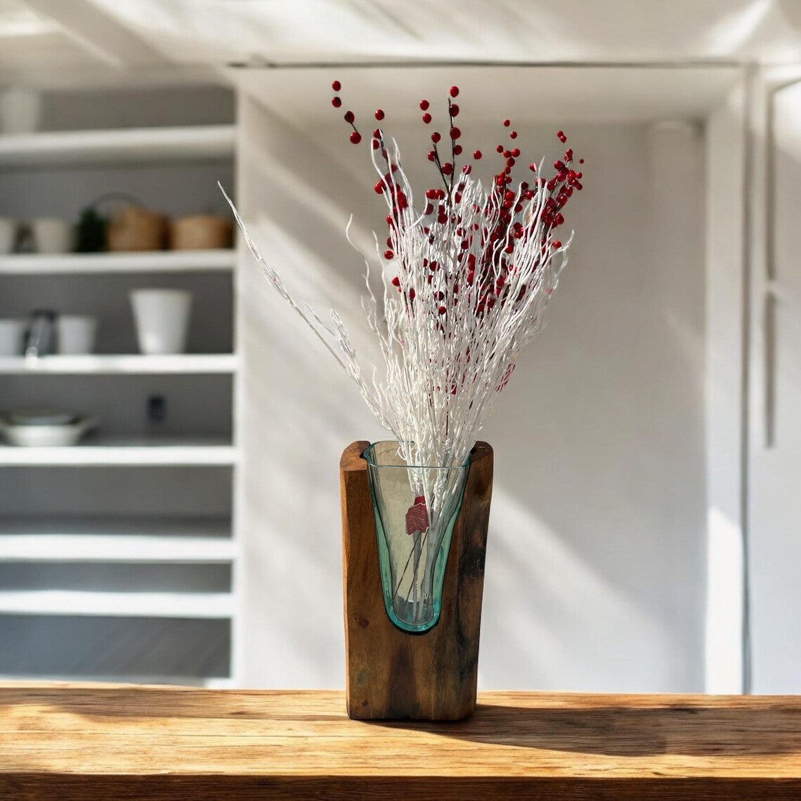 Teakwood vase with a glass insert containing red and white decorative elements on a wooden surface.