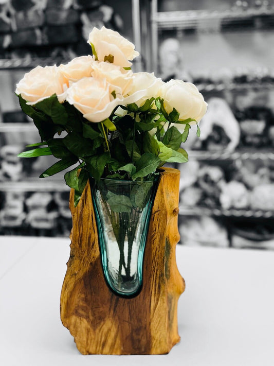 Glass vase with flowers in a wooden holder on a white surface