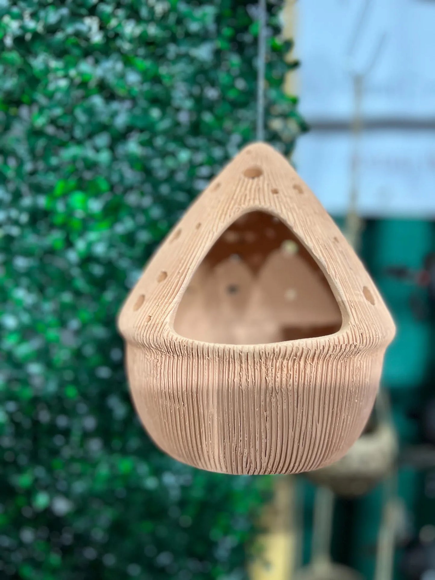 Beige textured Terracotta pots hanging against a green leafy background