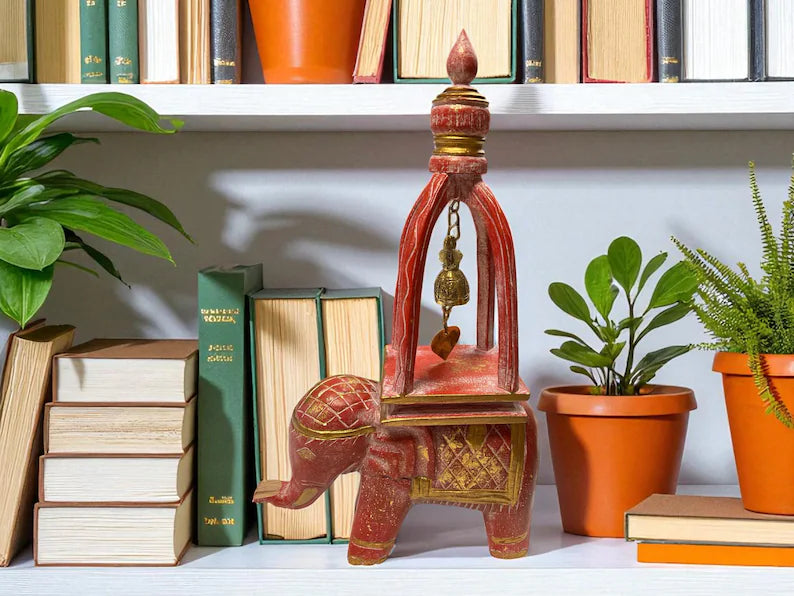 Decorative elephant statue with a lamp on a shelf with books and plants
