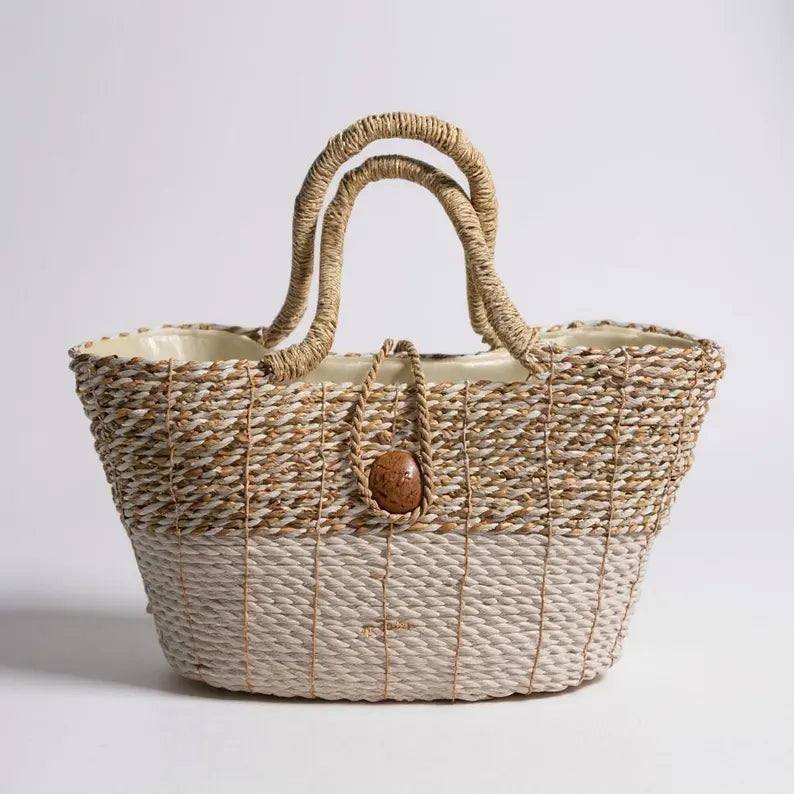 Woven straw bag with a wooden button on a light gray background