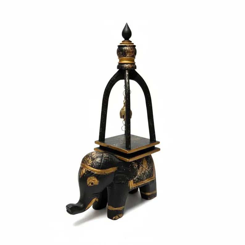 Decorative black and gold elephant with a tower-like structure on a white background