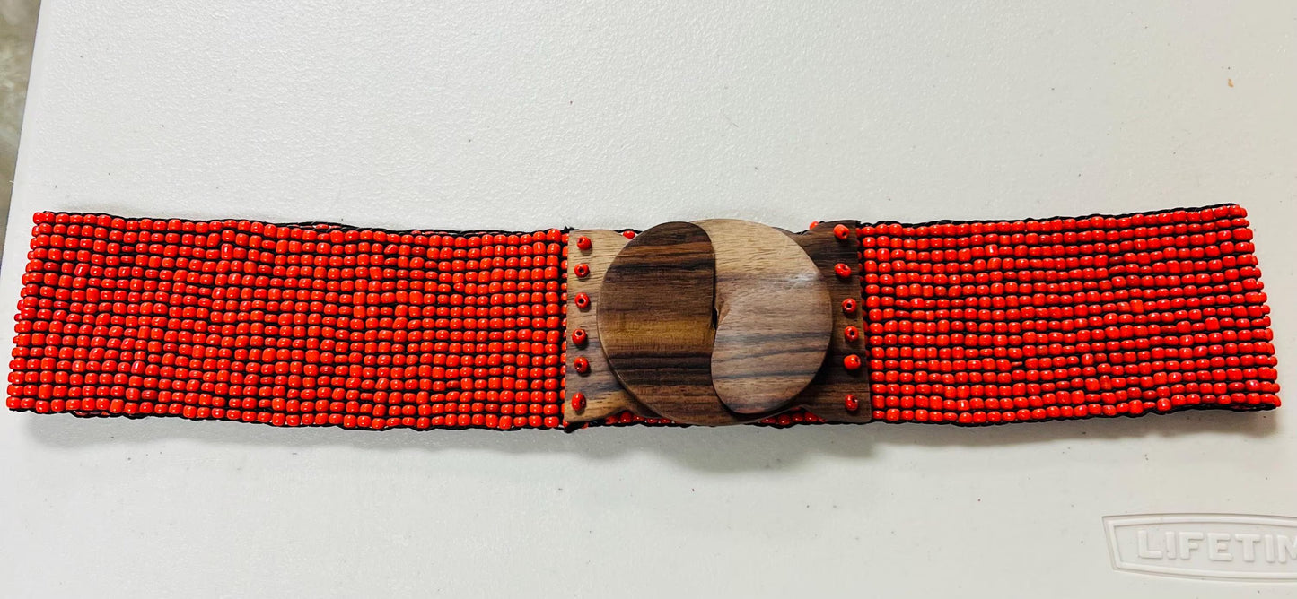 Red beaded belt with a wooden buckle on a light gray background